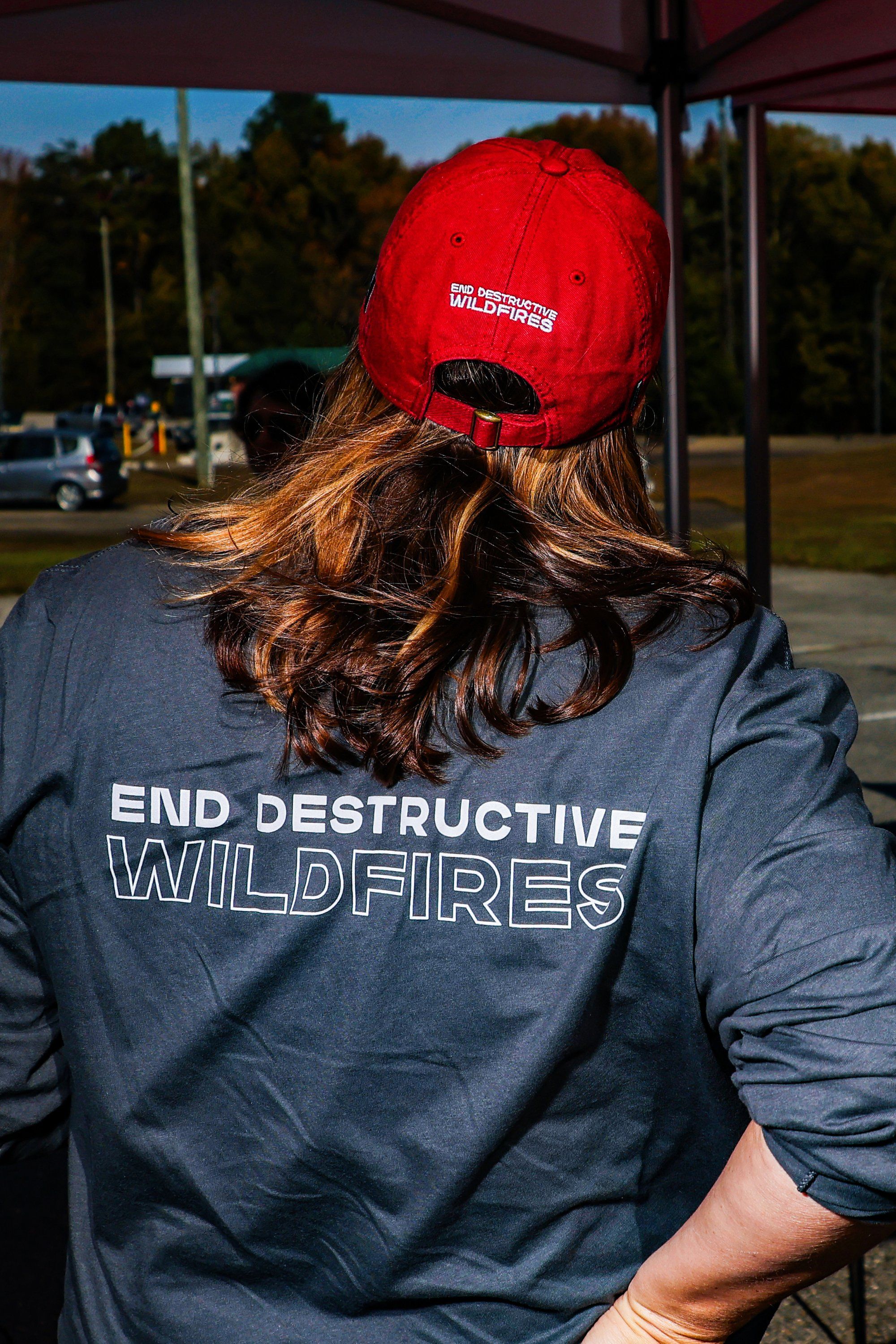 A woman in a blue jacket and red hat seen from behind.